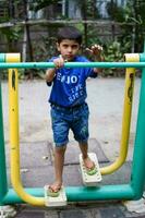 asiático chico haciendo rutina ejercicio en sociedad parque durante el Mañana tiempo. linda pequeño niño ejercicio y gimnasio a mantener él mismo ajuste para vida. niño ejercicio al aire libre disparar foto