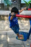 Asian boy doing routine exercise in society park during the morning time. Cute little kid exercise and gym to keep himself fit for life. Child's exercise outdoor shoot photo