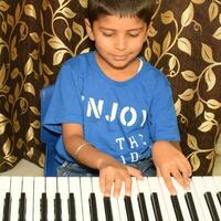 Asian boy playing the synthesizer or piano. Cute little kid learning how to play piano. Child's hands on the keyboard indoor. photo