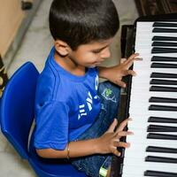 Asian boy playing the synthesizer or piano. Cute little kid learning how to play piano. Child's hands on the keyboard indoor. photo