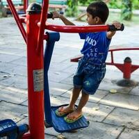 asiático chico haciendo rutina ejercicio en sociedad parque durante el Mañana tiempo. linda pequeño niño ejercicio y gimnasio a mantener él mismo ajuste para vida. niño ejercicio al aire libre disparar foto