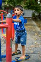 Asian boy doing routine exercise in society park during the morning time. Cute little kid exercise and gym to keep himself fit for life. Child's exercise outdoor shoot photo