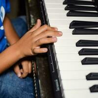 asiático chico jugando el sintetizador o piano. linda pequeño niño aprendizaje cómo a jugar piano. niño manos en el teclado interior. foto