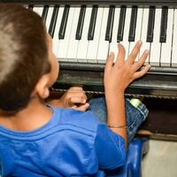 asiático chico jugando el sintetizador o piano. linda pequeño niño aprendizaje cómo a jugar piano. niño manos en el teclado interior. foto