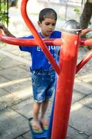 asiático chico haciendo rutina ejercicio en sociedad parque durante el Mañana tiempo. linda pequeño niño ejercicio y gimnasio a mantener él mismo ajuste para vida. niño ejercicio al aire libre disparar foto