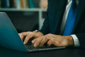 Close up. hand's business man wearing suit typing and working on laptop computer on wooden table at home office. Entrepreneur man working for business at home office. Working technology concept. photo