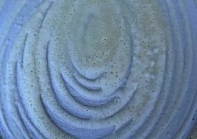 Close up textured of a spiral white cream on a blue pan background. photo