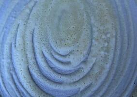 cerca arriba texturizado de un espiral blanco crema en un azul pan antecedentes. foto