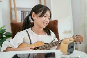 asiático pequeño niña sonriente y jugando ukelele felicidad momento foto