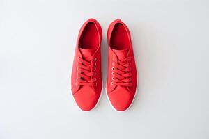 Pair of new stylish white sneakers on red background. International Red Sneakers Day. photo