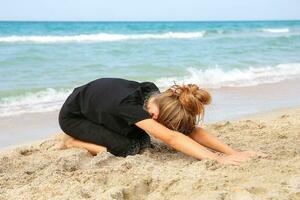 Girl practicing yoga on beach. photo