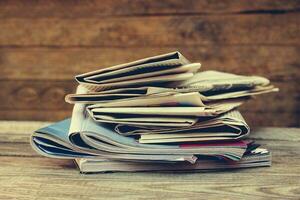 Newspapers and magazines on old wood background. Toned image. photo