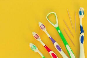 Toothbrushes, toothpick, tongue scraper on a yellow background. Top view. photo