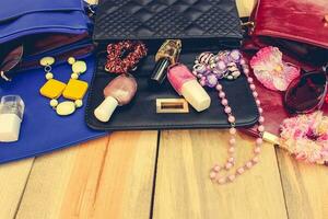 productos cosméticos y De las mujeres accesorios cayó fuera de diferente bolso. cosas desde abierto dama bolso. foto