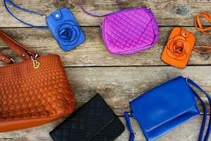 Colored handbags on wooden background. Top view. photo