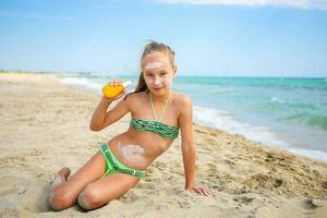 Girl applying protective sunscreen on face. photo