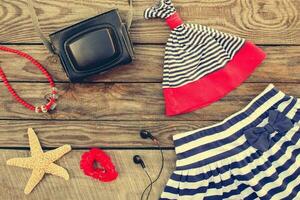 Summer children's clothing and beach accessories for your sea holiday on the old wooden background. Toned image. photo