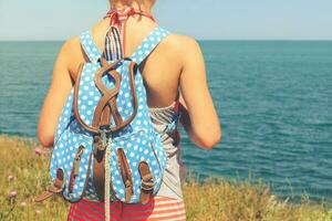 Girl with backpack looking at sea. Toned image. photo