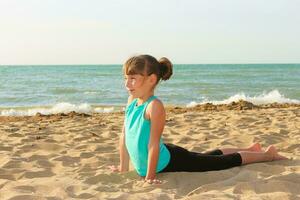 niña haciendo Deportes ejercicios en el playa. foto