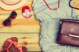 Women's summer clothing and accessories on wooden background. Toned image. photo