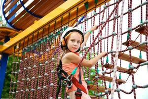 Happy girl on rope way in amusement center for children. photo