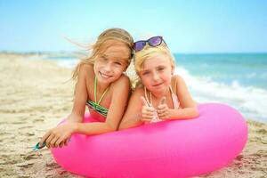 Happy girls lying on pink inflatable circle. photo