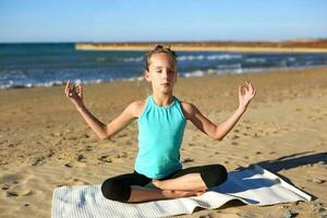 niña practicando yoga en el playa. foto