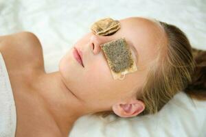 Beautiful girl with tea bags on eyes. Top view. photo