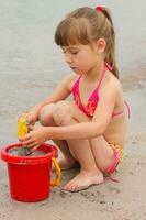 Girl playing with sand on the sea shore photo