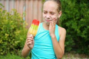 Girl has toothache from cold ice cream. photo
