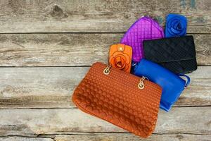 Colored handbags on wooden background. Top view. photo