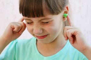 oído tapones a proteger en contra el ruido. niña cubierto su orejas. foto