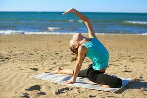niña practicando yoga en el playa. foto