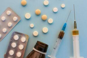 Pills, syringes on blue background. photo