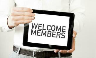 Text WELCOME MEMBERS on tablet display in businessman hands on the white background. Business concept photo