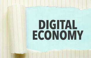 Text DIGITAL ECONOMY appearing behind torn white paper photo