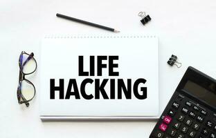 Business concept. Notebook with text LIFE HACKING sheet of white paper for notes, calculator, glasses, pencil, pen, in the white background photo