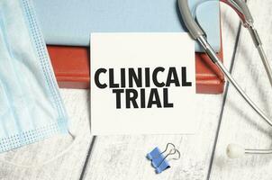 clinical trial on white paper and stethoscope on wooden desk photo