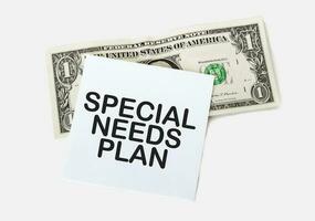 1 dollar bill and white notepad sheet on the white background. Text special needs plan photo