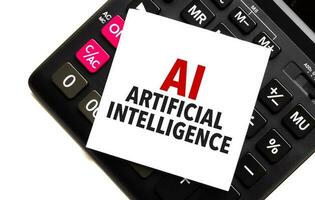 words AI - Artificial Intelligence on white sticker and calculator on white background photo