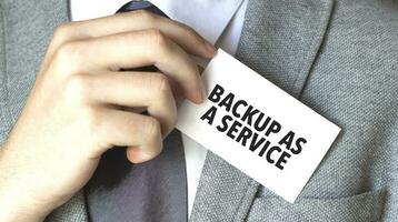 Businessman putting a card with text BACKUP AS A SERVICE in the pocket photo