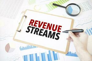 Text REVENUE STREAMS on white paper sheet and marker on businessman hand on the diagram. Business concept photo