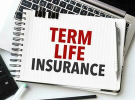 Keyboard of laptop, calculator, pencil and notepad with text TERM LIFE INSURANCE on the white background photo