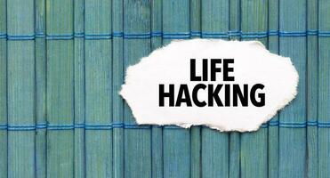 Text LIFE HACKING on the piece of paper on the green wood background photo