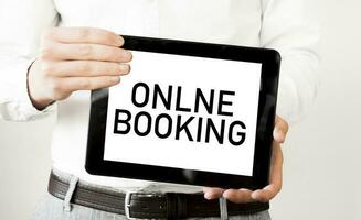 Text ONLINE BOOKING on tablet display in businessman hands on the white background. Business concept photo