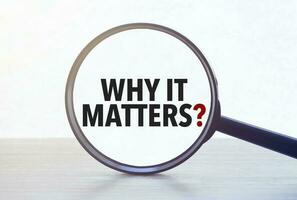 Magnifying glass with text why it matters on wooden table. photo