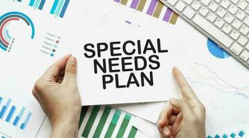 Businessman holding a card with text special needs plan .Keyboard, diagram and white background photo