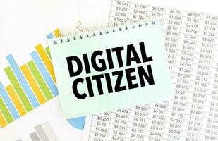 Green notepad on financial documentation. Text DIGITAL CITIZEN. Business concept photo