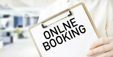 Text ONLINE BOOKING on white paper plate in businessman hands in office. Business concept photo