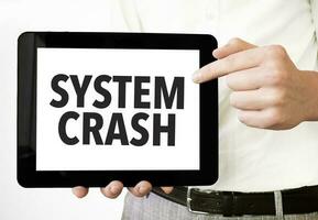 Text SYSTEM CRASH on tablet display in businessman hands on the white background. Business concept photo